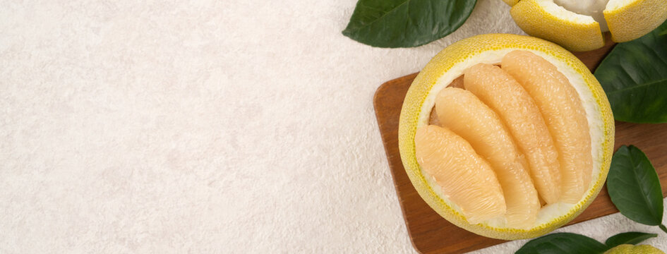 Fresh pomelo fruit with leaf on white table background.