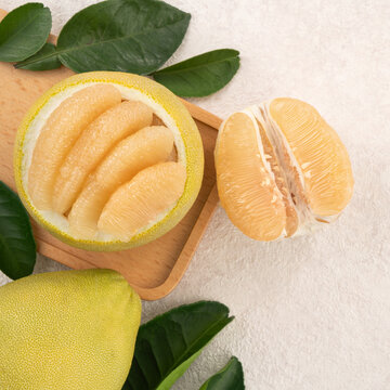 Fresh pomelo fruit with leaf on white table background.