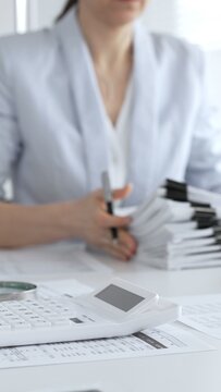 Business professionals collaborating at a desk, using a calculator and organizing financial documents for accounting, tax preparation, budgeting and corporate finance management. Audit and taxes