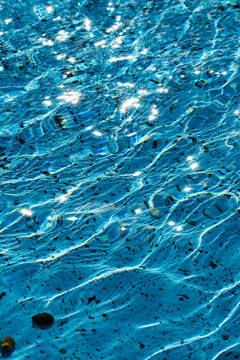 A close-up view of the detailed texture of the water in a pool or fountain, illuminated by the sun's rays	
