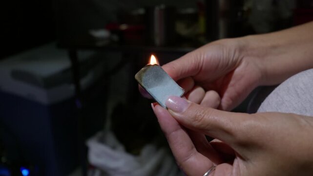 Hands hold and burn the edge of a mosquito repellent mat with an open flame at night. Detailed combustion sequence offers useful practical cutaway assets for outdoor safety guides.