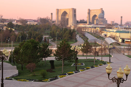 Bibi-Khanym Mosque in Samarkand seen from an elevated viewpoint at sunset with a landscaped park in the foreground. Ideal for travel guides, cultural publications, and tourism marketing.