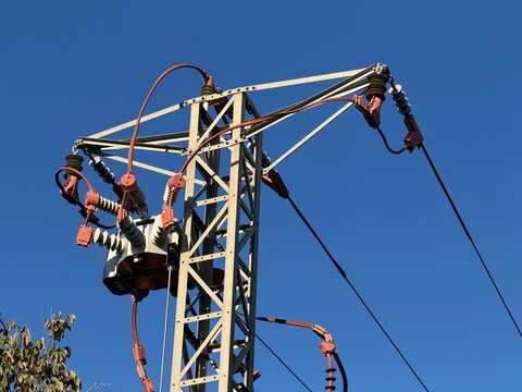 Electricity pylon with step down transformer, ceramic insulators and high voltage cables against a clear blue sky, representing power distribution in calvia, balearic islands, copy space