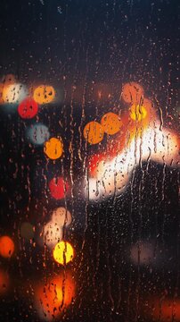 Raindrops Sliding Down Window Glass with Blurred Warm City Lights at Night, Rainy Bokeh Background, Moody Urban Atmosphere, Vertical