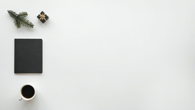 A flat lay composition on a white background, featuring a black, notebook, a cup, of black coffee, a small gift, box, and a, sprig of pine, needles for a, festive mood