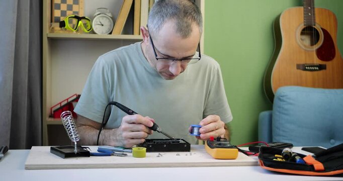 Technician tests computer hard drive with multimeter at organized workstation. Small business electronics repair concept featuring diagnostics, maintenance and hands-on technical service.