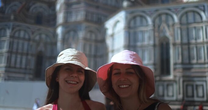 Two young women friends having fun smiling on camera with Florence city in background - Travel, vacation and friendship concept - UGC content