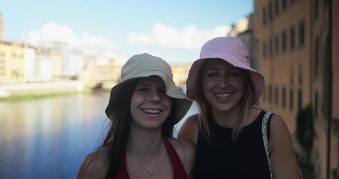 Happy girls smiling on camera with river in background during city trip vacation - Holiday, young people and travel concept - UGC content