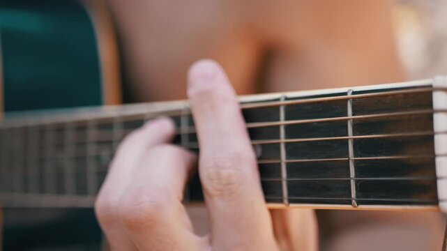 Close-up of a musician pressing strings into a bar chord on an acoustic guitar fretboard. The focus highlights precise finger placement and clean technical mechanics for lessons.