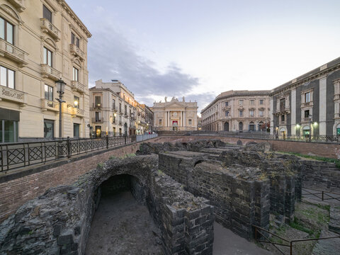 Sunken volcanic ruins of the Roman Amphitheatre at Piazza Stesicoro with San Biagio church in Catania, Sicily, Italy.
