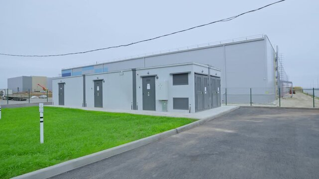 Modular transformer station occupies industrial area. Prefabricated construction provides practical and organized technical solution