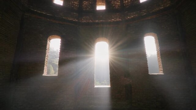 Sunbeams through ancient circular architecture creating dramatic atmospheric light and shadow play
