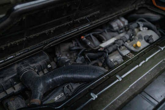 Detailed view of an old automobile engine compartment covered in dust, grime, and grease, showing mechanical parts in need of maintenance, cleaning, or repair.