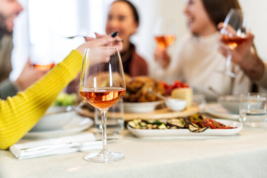 Happy family having dining at home drinking red wine - Close up view of wineglass on dinner table