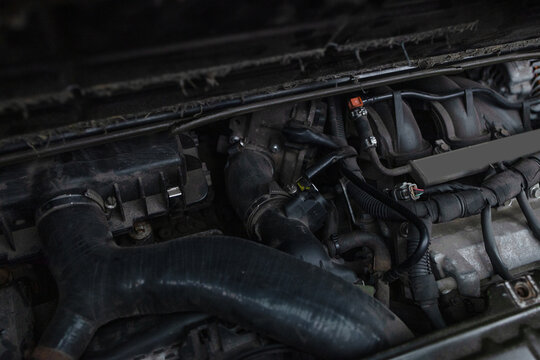 Detailed view of an old automobile engine compartment covered in dust, grime, and grease, showing mechanical parts in need of maintenance, cleaning, or repair.