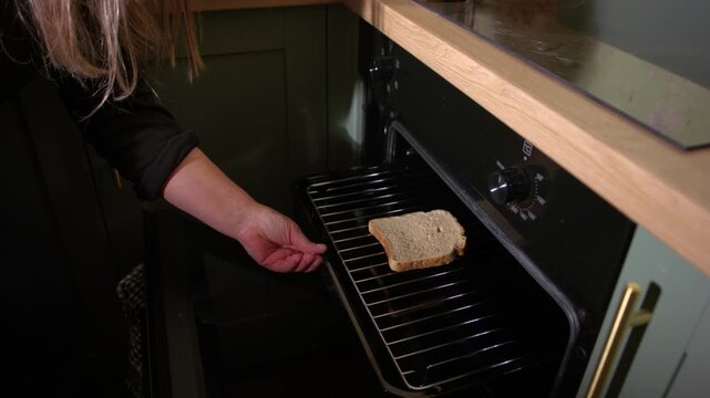 Woman putting slice of bread in oven grill to make toast