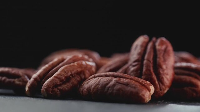 Macro shot of fresh premium pecan nuts with selective focus, sliding camera shot on dark background with artistic lighting. Perfect for healthy eating, gourmet food, culinary, and dietary content.
