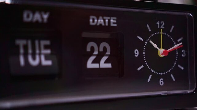 Classic mechanical flip clock with day, date flip cards and round analog face. Vintage timepiece close-up, retro decor, time passing concept.