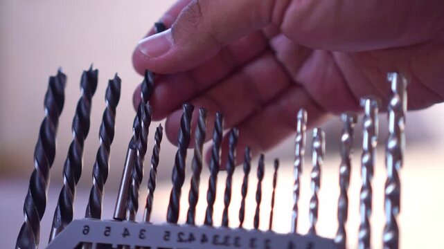 fingers placing drill bit into sorted case, hardware tool storage, DIY workshop footage scene.