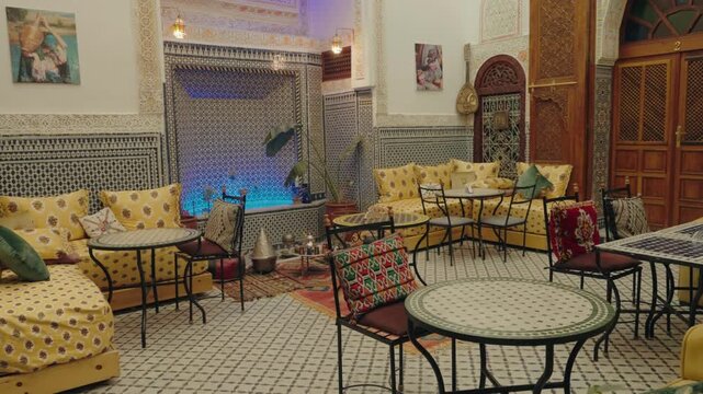 Traditional Moroccan courtyard with ornate tilework, vibrant cushions, and a tranquil fountain. This inviting space offers a glimpse into Moroccan culture and hospitality, travel or lifestyle content.