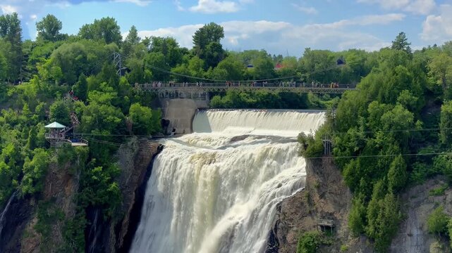 Wide shot of Montmorency Falls with people crossing the suspension bridge in Quebec City, Quebec, Canada. 