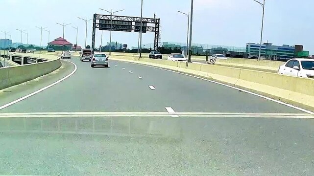 Vehicles driving on multi lane highway bridge with steady traffic flow during bright daytime conditions
