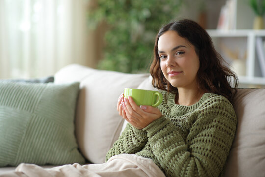 Young woman looking at you drinking coffee in winter
