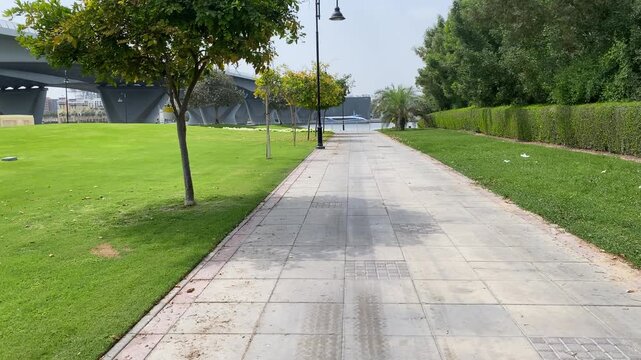 Landscaped parkway alongside Dubai Creek, offering lush greenery and scenic urban waterfront views in Deira.