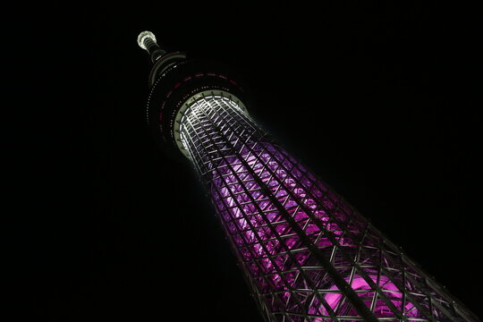 The Tokyo Skytree glows with purple lights at night.