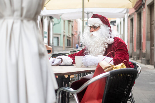 Tired Santa Claus resting at cafe with coffee