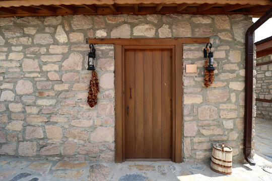 A stone house built in the traditional architectural style. The building's old wall and brown wooden door.