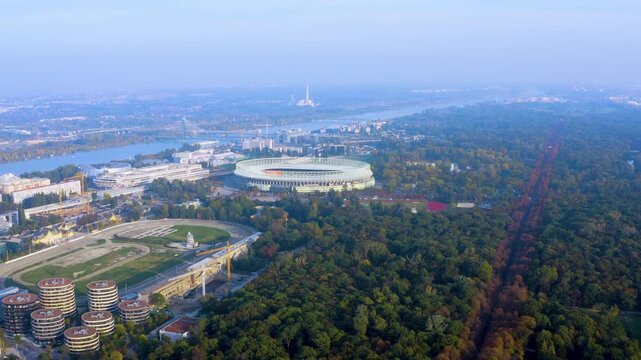 Aerial drone view of the Ernst Happel Stadium in Vienna with the Prater park and Hauptallee in autumn colors, Krieau trotting track, residential towers and the Danube River, Austria.