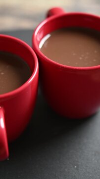 Rotating cups of hot chocolate on wooden table