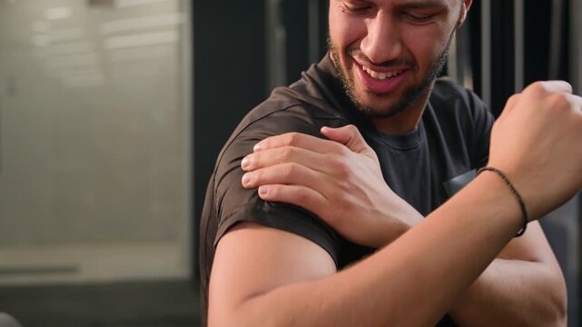 Sad African American man male athlete holding painful shoulder in gym after workout tired ethnic bodybuilder suffering arm injury ache discomfort following intense fitness exercise sport club recovery