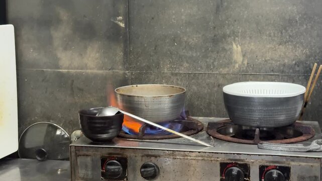 Gas flames under pots on an old commercial stove in a restaurant kitchen