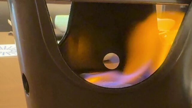 Close-up of solid fuel flame burning in a tabletop hot pot burner at a Japanese ryokan dinner