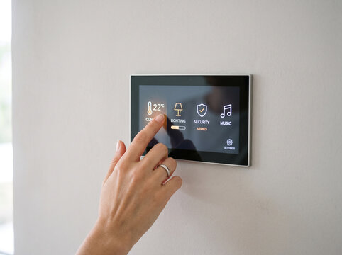 Woman Hand Using Smart Home Control Panel on Wall for Climate and Lighting Automation