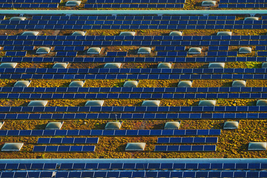 Aerial perspective of a modern industrial facility with solar panels on the industrial roof with patches of green moss.