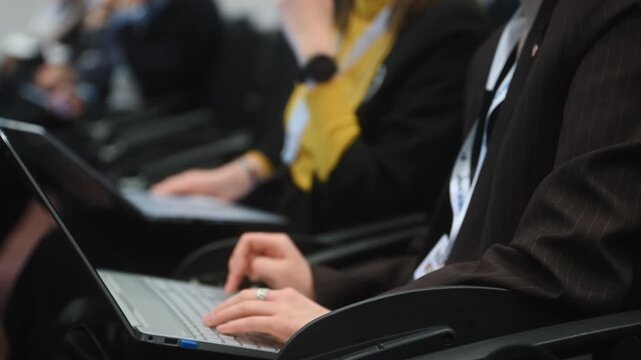 Close-up of conference attendee using a laptop to take notes during a professional event. Universal concept of business conference, learning and information.