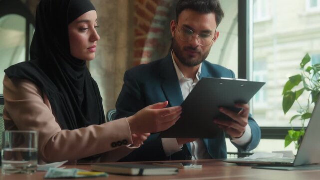 Two Hindu diverse business team signing documets in office workplace Arabian executives businessman businesswoman in hijab sign contract startup project papers together partnership businesspeople job