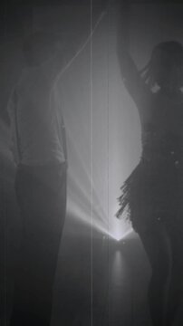 1920s old style black and white color silhouette romantic happy couple dancing together in dark night club. woman flapper with man have fun at dance floor retro party roaring twenties. vertical video