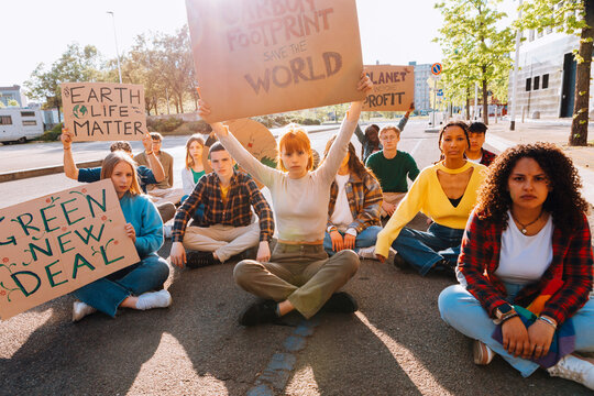 Young woman raises a protest sign above her head during a climate demonstration