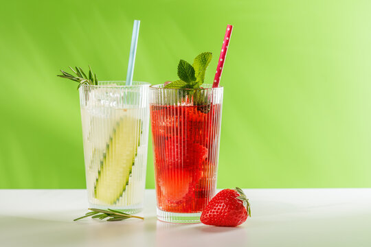 Fresh non alcoholic berry and cucumber drinks with herbs on green background