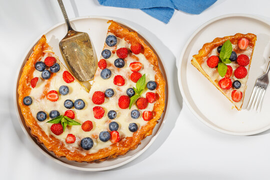 Slice of berry tart served on plate beside whole pie