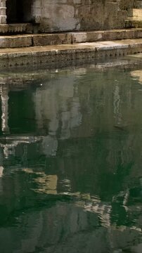 Water ripples reflect the walls of Toorji Ka Jhalra Baoli stepwell in Jodhpur, Rajasthan, India. Vertical camera tilt