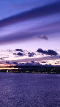 Evening view of the 25th of April Bridge linking Lisbon and Almada on the Setubal Peninsula, with boats on the Tagus River, Portugal. Camera pan