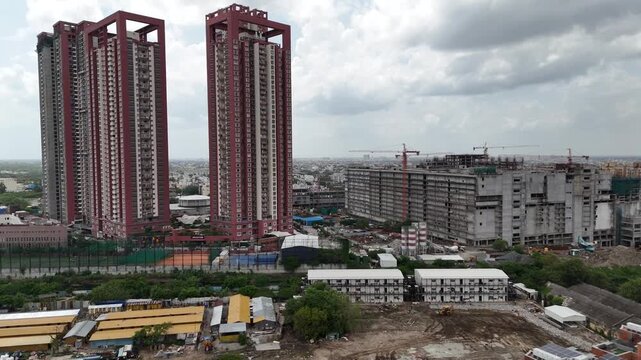 Cinematic aerial drone view of SPR City, Perambur, Chennai, featuring two prominent red-and-white high-rise residential towers surrounded by large-scale commercial and residential construction.