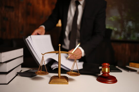 Lawyer Reviewing and Writing Legal Documents with Scales of Justice and Gavel on Desk