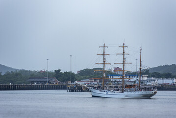 Traditional sailing ship departing a major maritime waterway and heading toward the open Pacific Ocean, surrounded by tropical scenery and calm coastal waters. © Mariusz