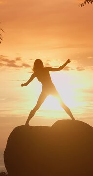 Young Woman Practicing Yoga Poses on a Rock at Sunset